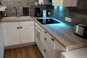 Der Herd verfügt neben dem Backofen über ein modernes Ceranfeld. Küchenblock beleuchtet.